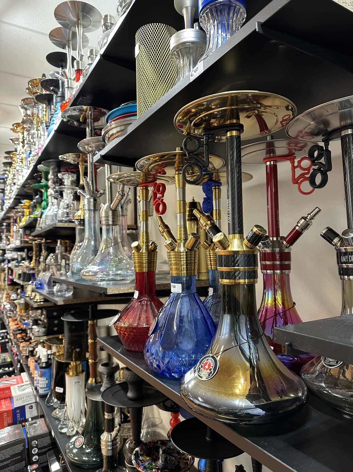 Schappen vol kleurrijke glazen waterpijpen en accessoires in onze shisha winkel in Almere, met het breedste assortiment direct op voorraad.